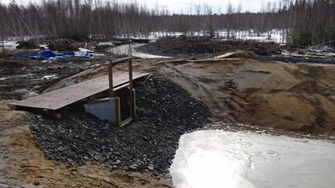 Etualalla lietteenkuivatusaltaan pato ja taustalla lietteenkeruualtaan pato. Taaempana näkyy lietteenkeruualtaalle johtava uusi kanava